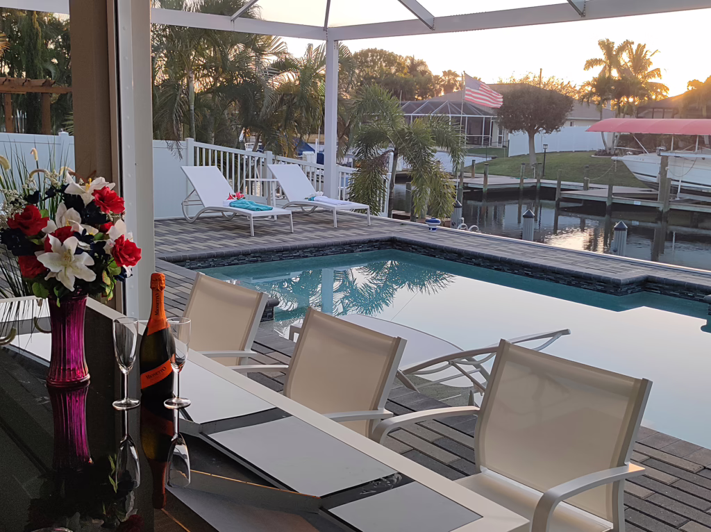 Poolside dining area with champagne, flowers and canal view at sunset – Villa Dandelion Cape Coral Florida